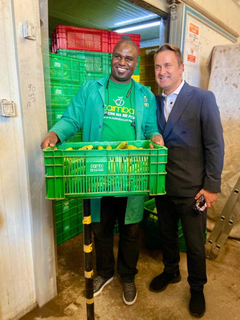 Luxembourg's Deputy Prime Minister and Minister of Trade and Foreign Affairs interacting with a smallholder farmer holding bananas