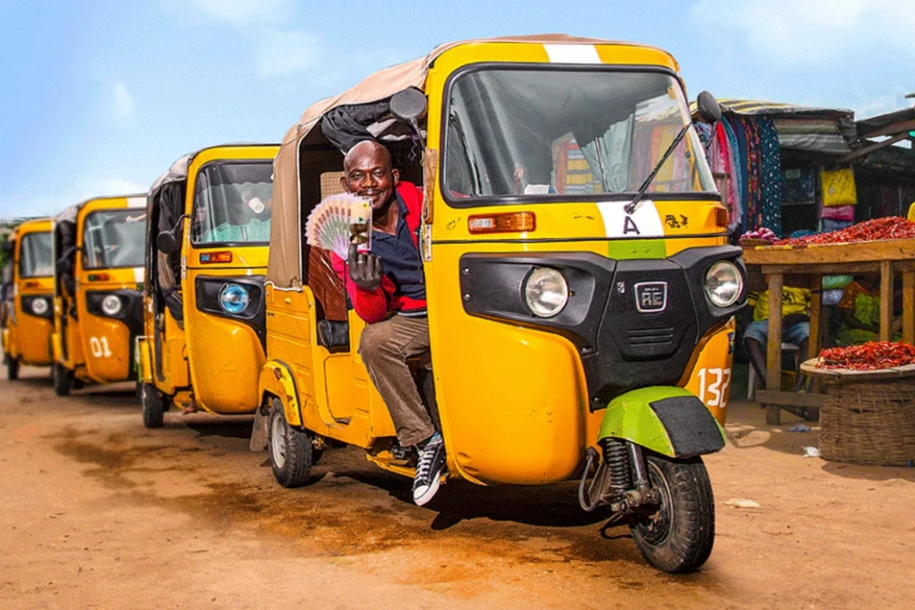 A man sits in a yellow Bajaj tuk tuk