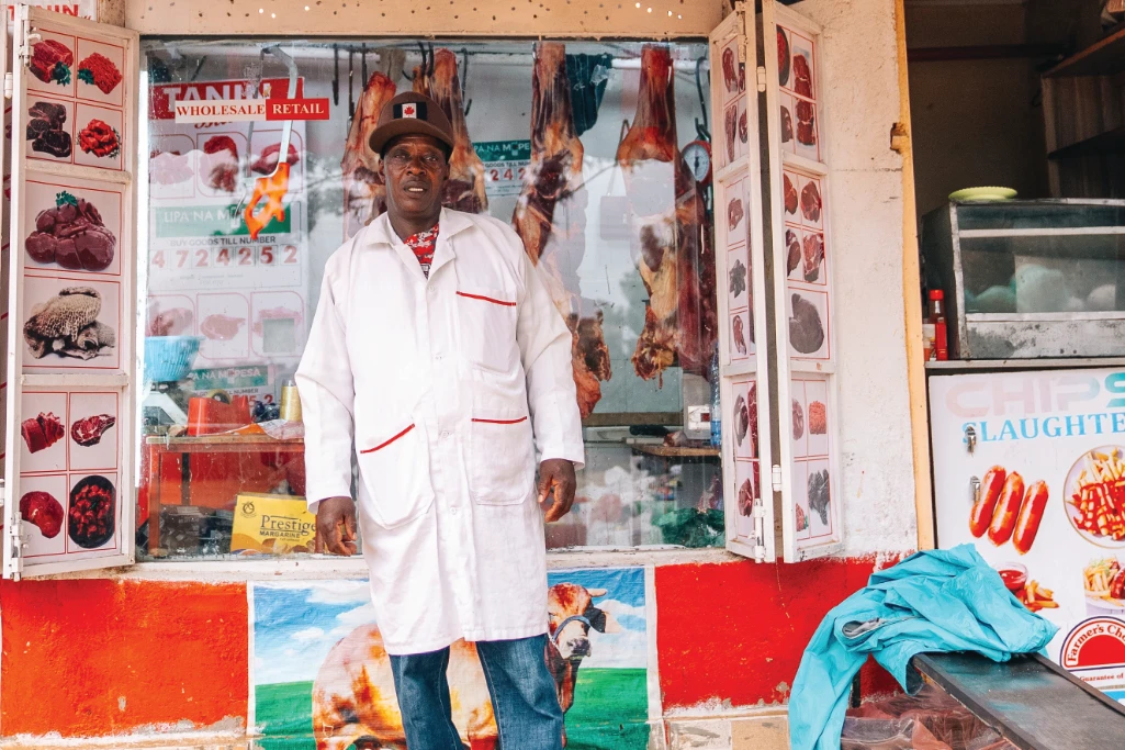 A butcher stands outside of his store in Kenya