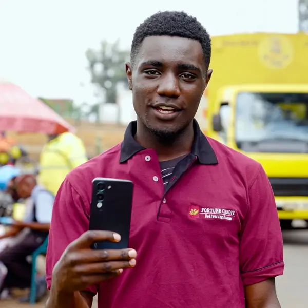 A man wears a Fortune Credit golf-shirt and holds the phone he took a loan out for
